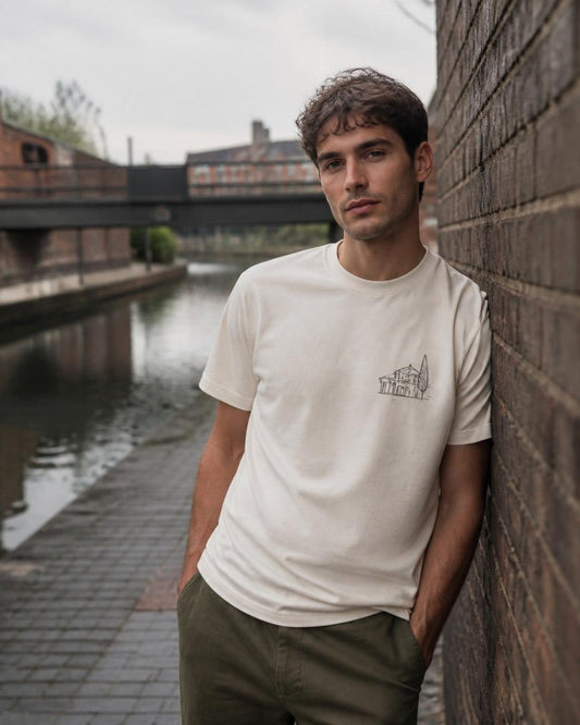 Man in an off-white printed t-shirt leaning on a brick wall by a Birmingham canal
